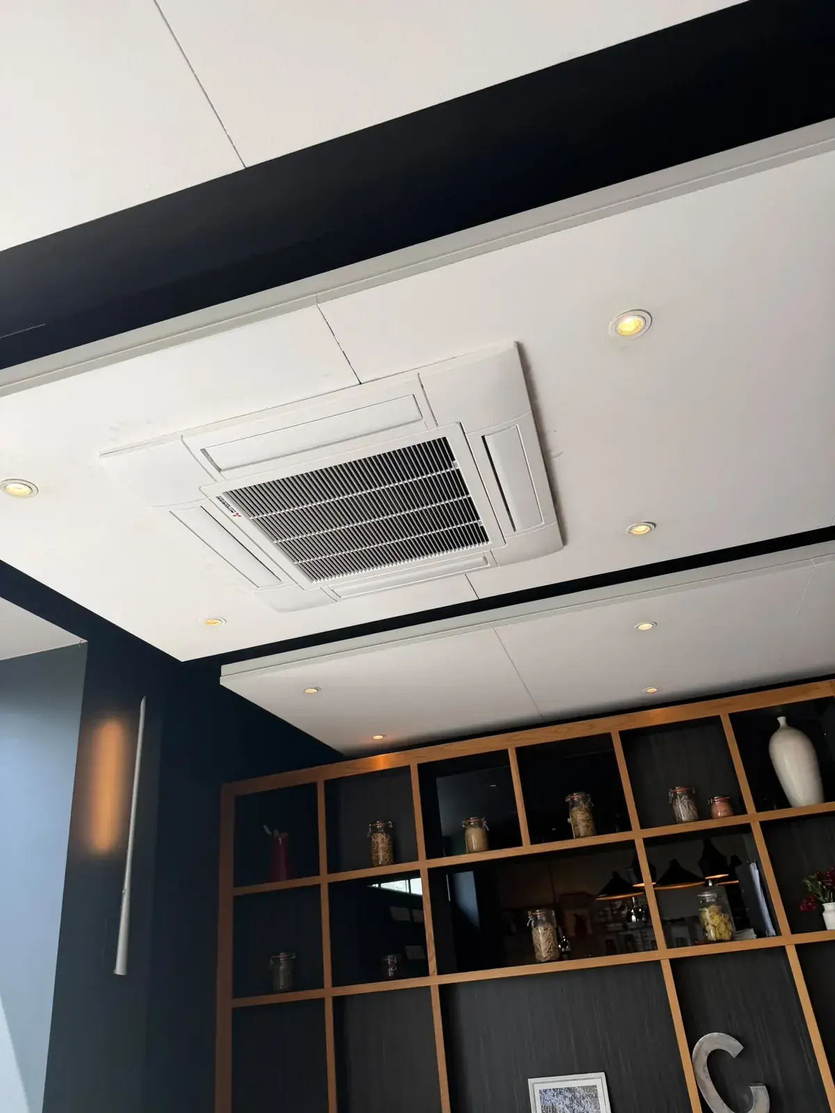 Ceiling cassette air conditioning unit in a modern interior above display shelving