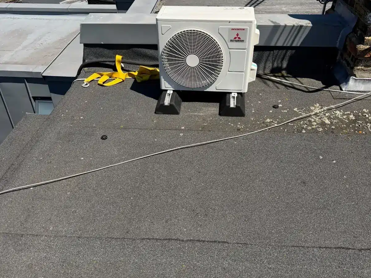 Mitsubishi Electric outdoor unit on a flat roof beside a skylight