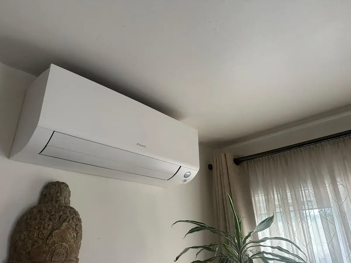 Daikin wall-mounted air conditioning unit above sheer curtains in a living room