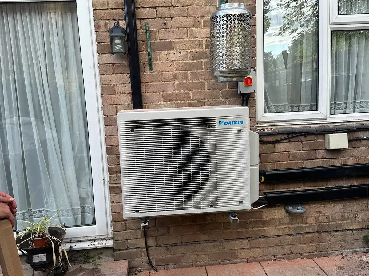 Daikin outdoor unit on a brick wall between a patio door and a window