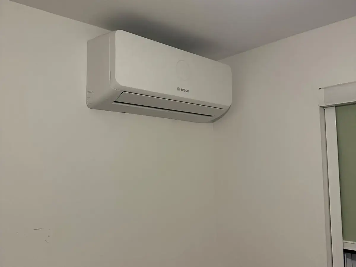 Bosch wall-mounted air conditioning unit in the corner of a plain room