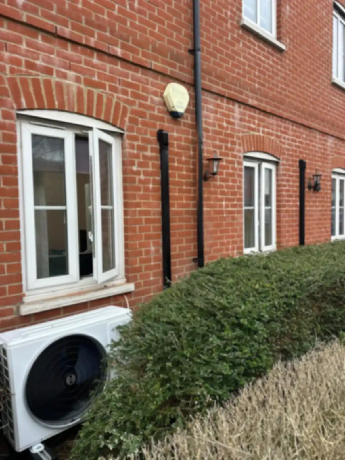 Air conditioning outdoor unit installed beside a red-brick residential building