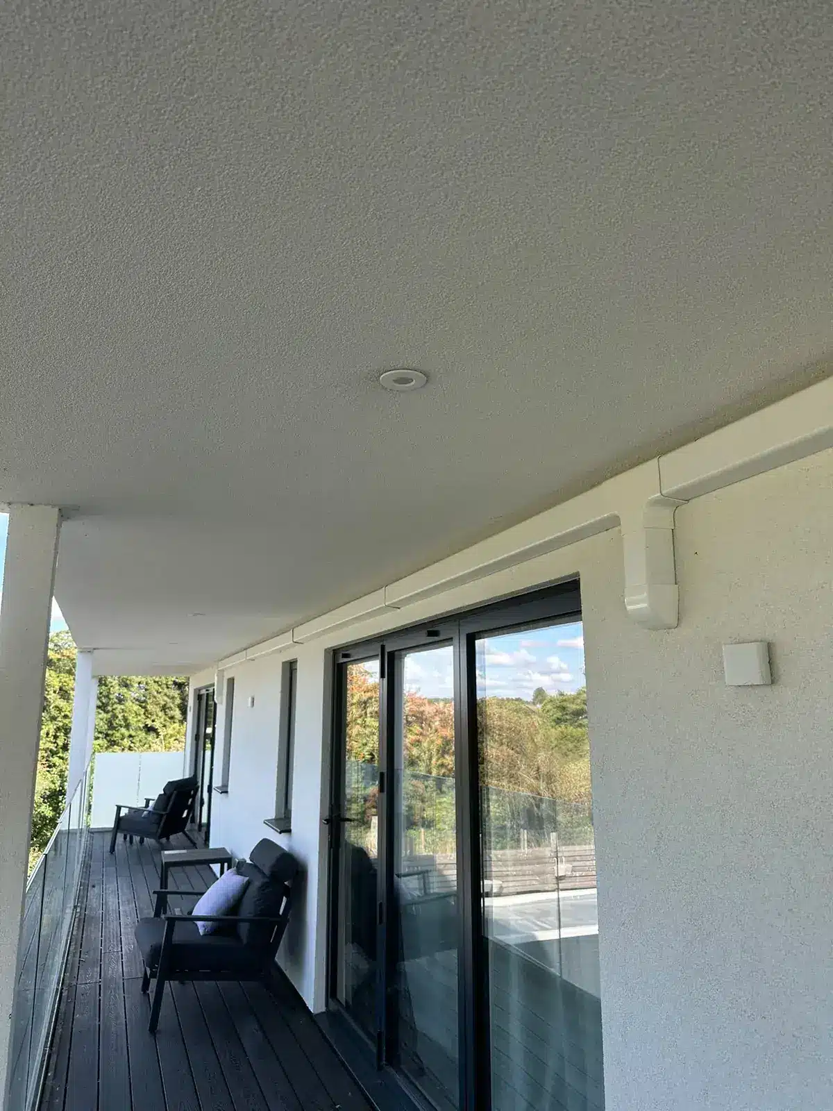 Covered balcony of a modern apartment with sliding doors and white service trunking on the wall
