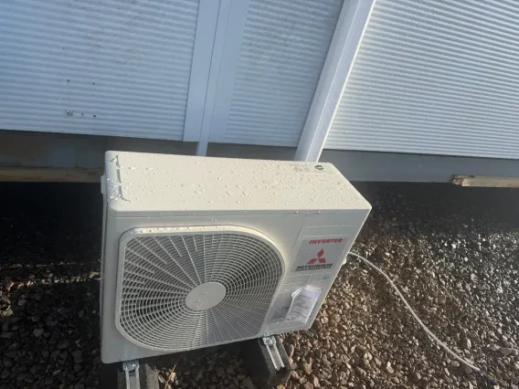 Mitsubishi Electric outdoor unit on a gravel roof beneath a building overhang