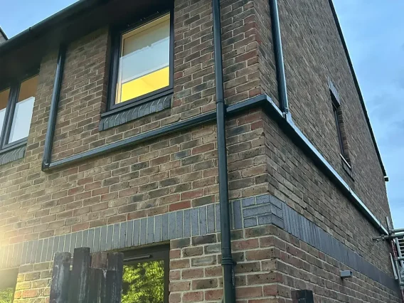 Pipe trunking run around the corner of a two-storey brick house