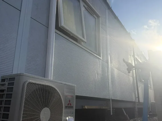 Mitsubishi Electric outdoor unit beside a clad modular building in bright sunlight