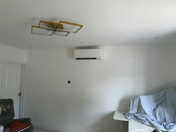 Wall-mounted air conditioning unit high on the wall of a freshly decorated room