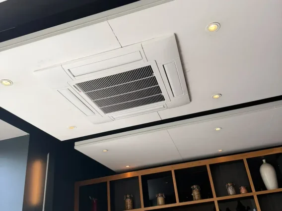 Ceiling cassette air conditioning unit with spotlights above wooden display shelving