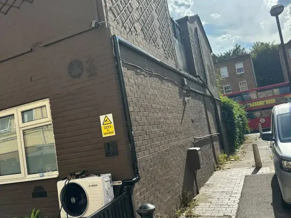 Bosch outdoor unit at the base of a brick commercial building beside a street